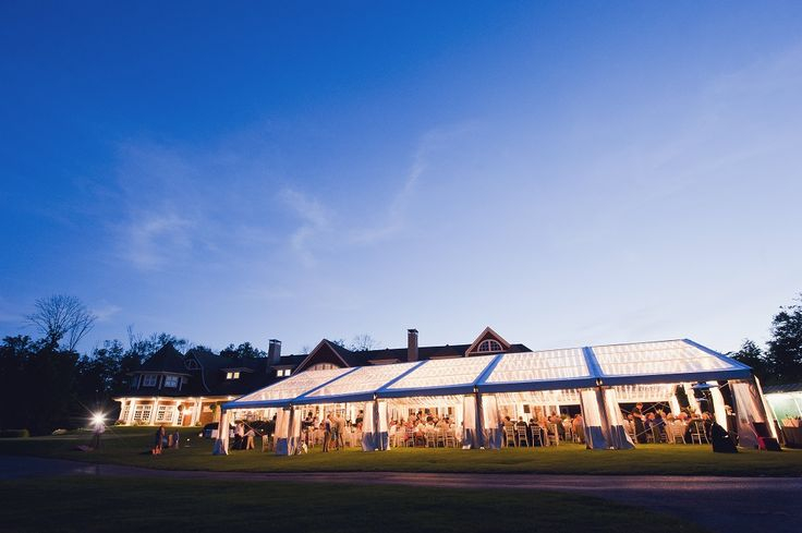 Clear tent with wedding guests celebrating on event lawn